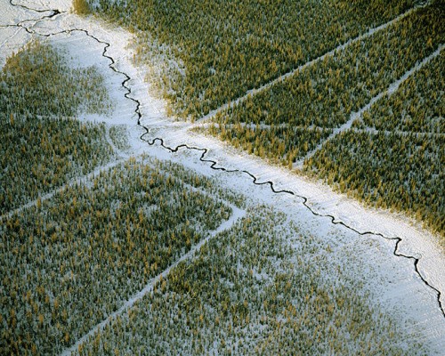 Cracked frozen river running through green land
