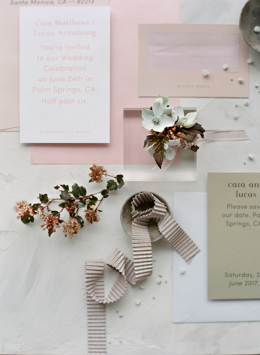 A photo that shows a modern wedding invitation in white, taupe, beige, and light pink.