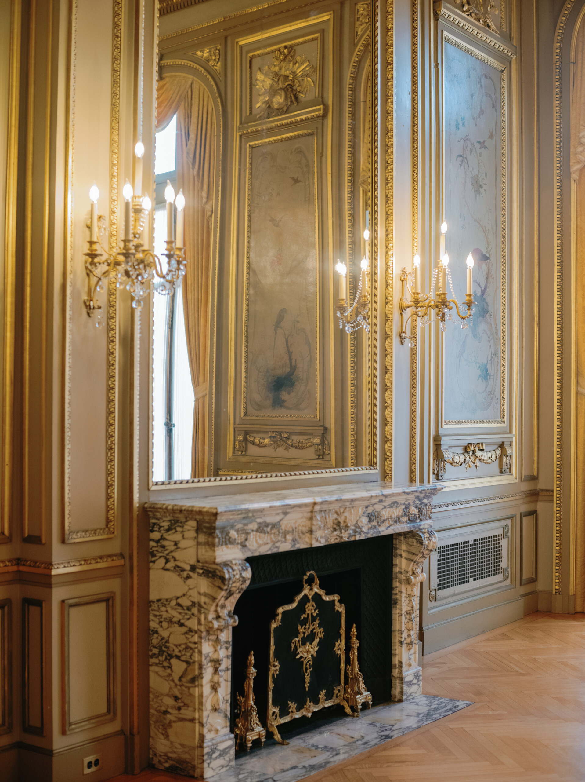 A guilded fireplace in a gold and cream ballroomin in a historic building in Washington, D.C